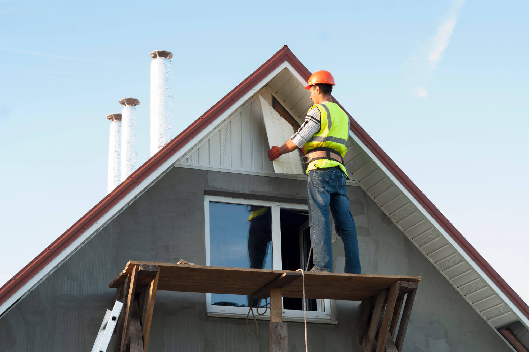 Construction worker mounting a soffit on roof eaves