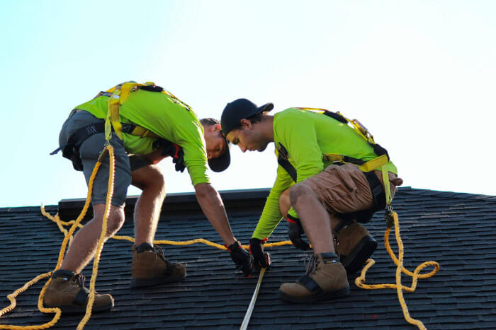 Two roofers measuring on a roof